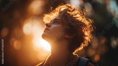 Sunlit forest youth's upward gaze and nature's inspiring portrait