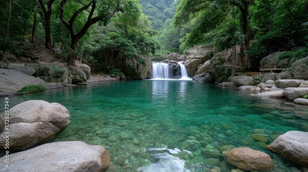 Naklejka premium Waterfall Cascading Into Emerald Pool Surrounded By Lush Tropical Foliage and Trees in Verdant Forest with Rocks and Clear Water in Daylight