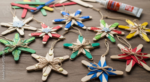 Colorful homemade christmas star ornaments made from popsicle sticks and glue on a wooden table, diy holiday craft project, top view