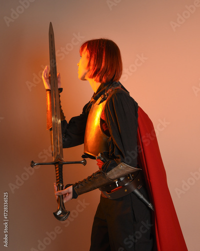portrait of Fantasy warrior woman model, holding sword weapon, historical medieval armour costume with red fairytale cloak, strong fantasy knight. isolated studio background golden cinematic lighting.