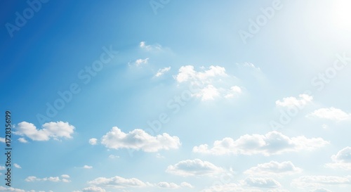 Fotografi Vibrant blue sky filled with fluffy white clouds and gentle sunbeams creating a serene and uplifting atmosphere, perfect for aspirational and peaceful projects