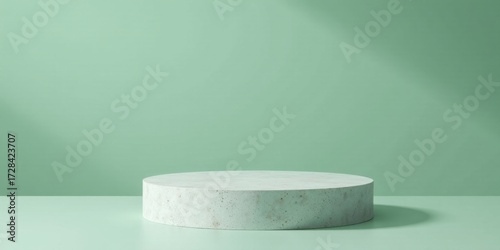 A serene minimalist display featuring a speckled light grey circular platform against a soft mint green backdrop, ideal for showcasing products or concepts.