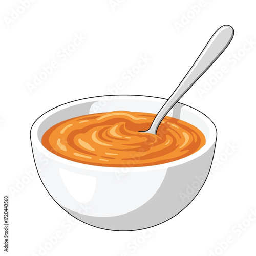 A white bowl filled with orange soup, with a silver spoon resting inside.