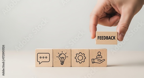 Hand placing feedback block on wooden cubes with business icons
