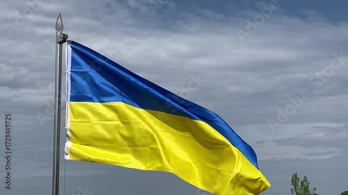 Large yellow and blue flag of Ukraine waves against the cloudy sky. National state symbol of Ukraine.