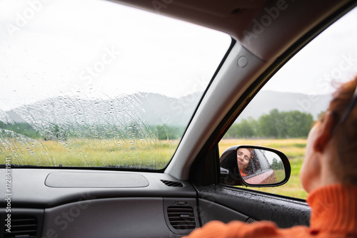 Wallpaper Mural Woman relaxing in a car during the rain in the forest. Green forest and mountains in the background. Torontodigital.ca