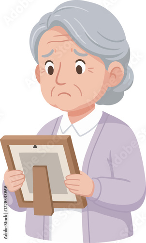 An elderly woman, with a sad expression, holds a framed photograph, contemplating.