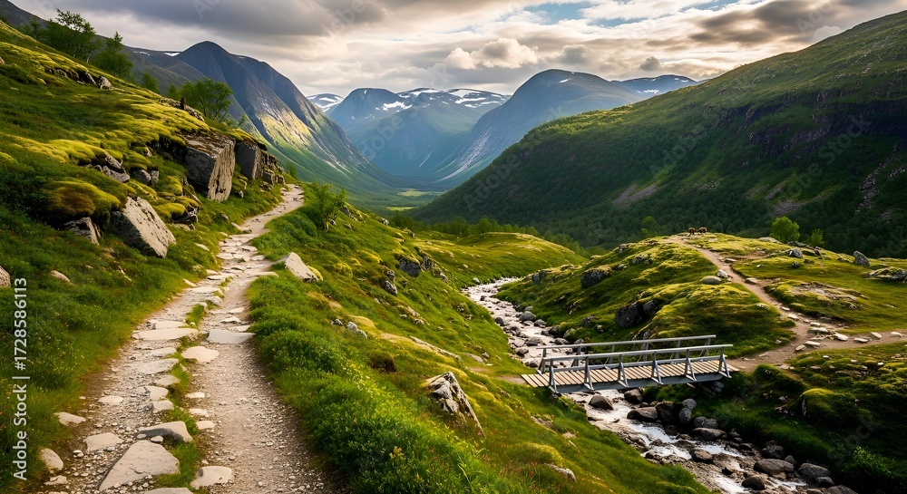 Fototapeta premium A stunning, lush green valley in the Norwegian mountains. A winding stone hiking path leads past a rushing river and a small bridge, set beneath a dramatic, cloudy sky