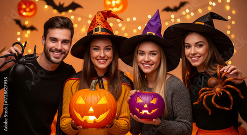 Smiling group in Halloween costumes, holding pumpkins and spiders against a festive background, showcasing a fun and celebratory Halloween atmosphere