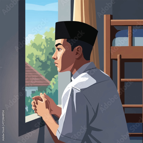 A young Muslim man in a peci cap looks thoughtfully out of a sunlit window from his room.