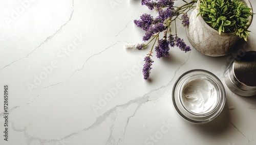 A pristine white marble surface displays a jar of luxurious cream, adorned with a bouquet of purple blossoms and a small potted plant.