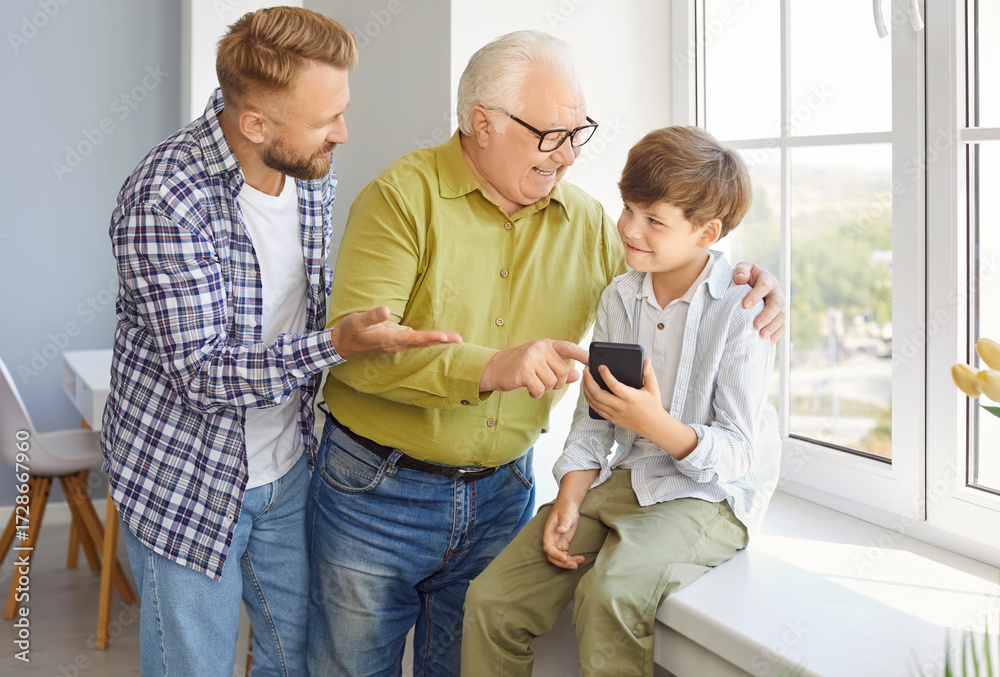 Obraz premium Happy family of three generation men, grandfather, father, son, cute child grandson playing smartphone, using phone together, looking at phone screen, chatting or shopping online, father's day holiday