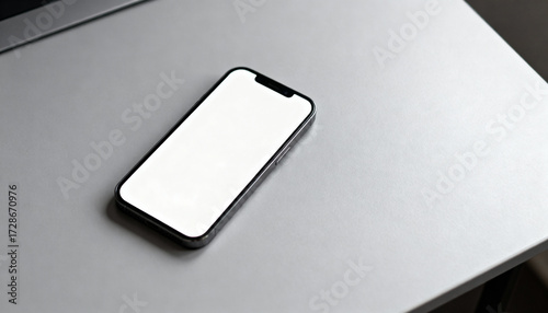 Mobile phone with an empty screen mockup for a design presentation. Smartphone on a silver laptop surface. Modern device with a blank display for advertising or app interface showcase.