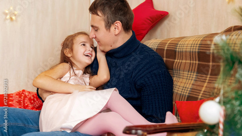 Father and daughter playing together in front of the Christmas tree