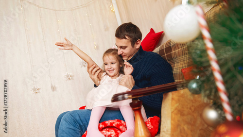 Father and daughter playing together in front of the Christmas tree