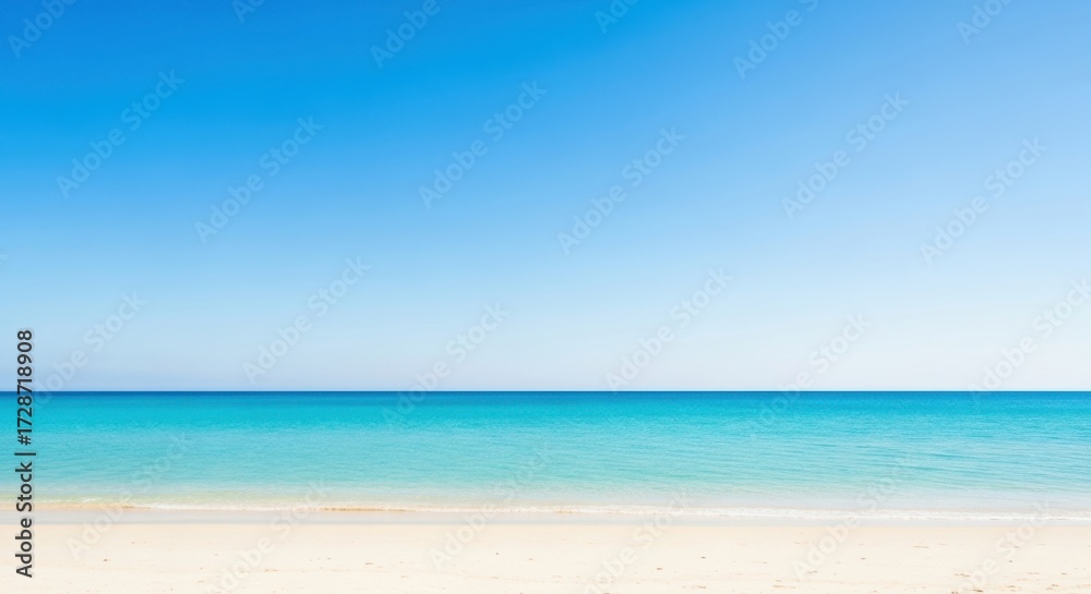 Fototapeta premium Serene ocean horizon with soft sand beach under a bright blue sky