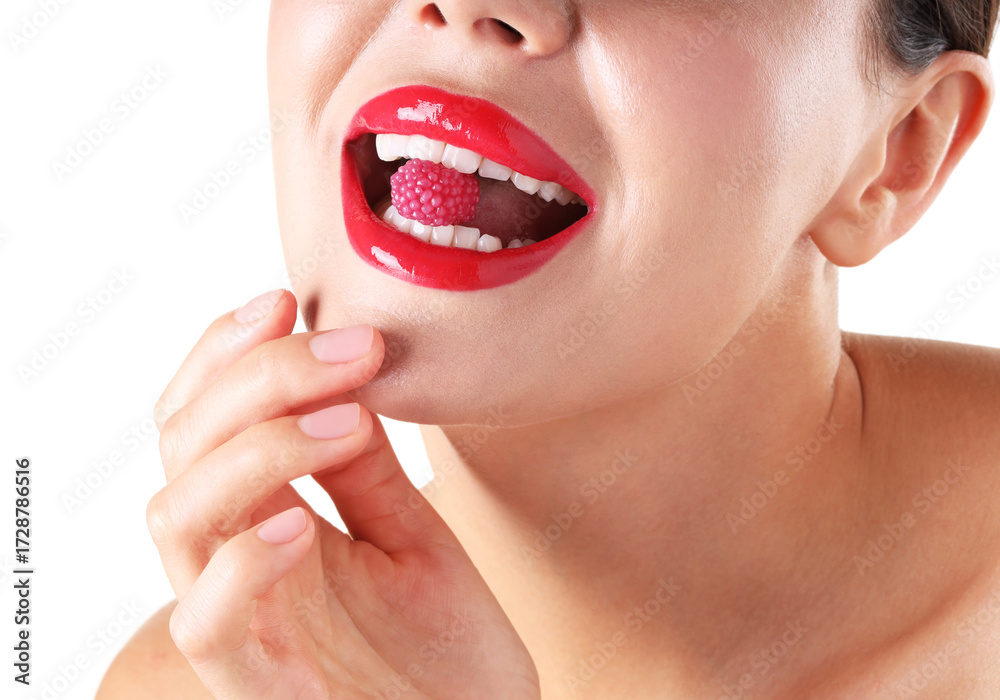 Obraz premium Woman with beautiful red lipstick on her lips and raspberry candy against white background, closeup