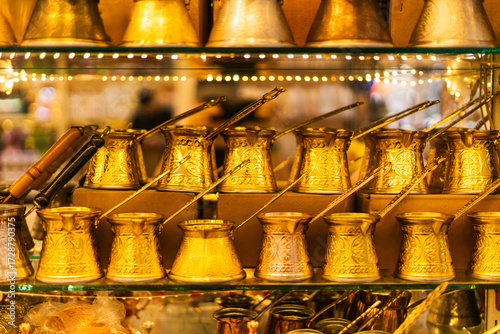 Rows of crafted coffee pots gleam under warm lights in a bustling market. Each pot reflects traditional designs, showcasing skilled artisanship and cultural heritage