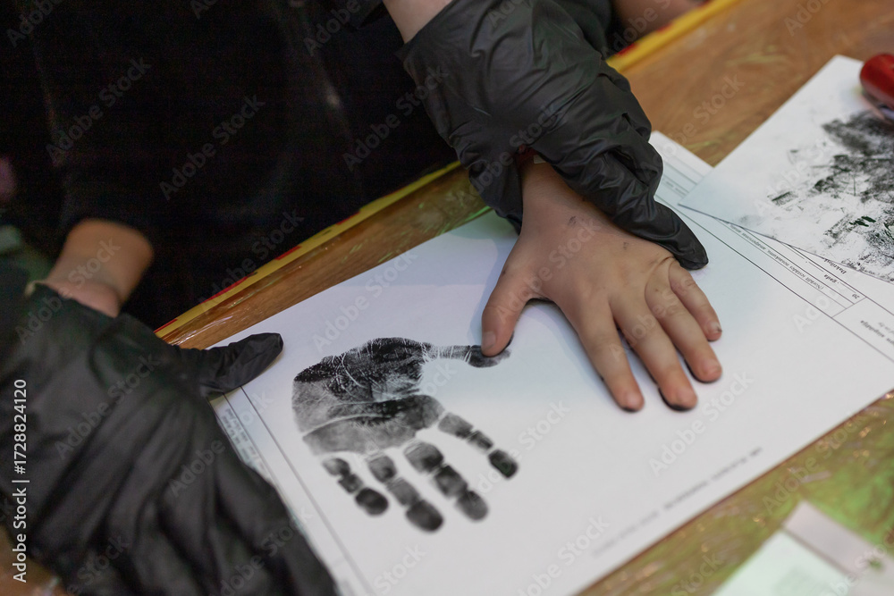 Obraz premium Taking of suspect's fingerprints in police department, close-up. Hand print on paper in black-white