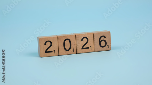 2026 Happy New Year concept with wooden cube blocks changing from 2025 to 2026 on blue background, minimal design symbolizing time change and new beginnings.