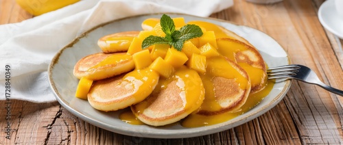 Plate of golden cottage cheese pancakes with sweet mango sauce on top