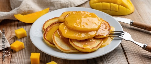 Plate of golden cottage cheese pancakes with sweet mango sauce on top