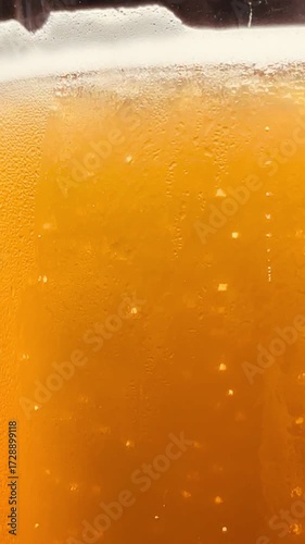 A glass of beer is full and has bubbles in it. The beer is yellow in color