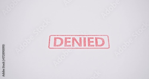 A video footage showing a close-up of a hand using a red rubber stamp to mark the word 