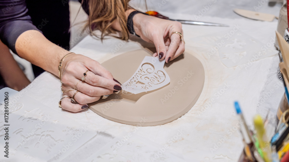 Obraz premium During an art event in a studio, middle age woman is painting Christmas ornament shapes she crafted on clay