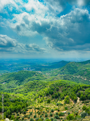 Scenic landscape view from a hilltop with lush green forests and distant mountains under a cloudy sky