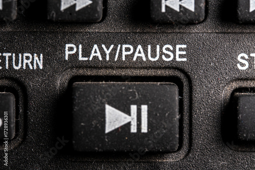 Tv play and pause icon and button close up of a old dusty black Television remote controller