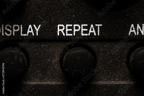 Tv repeat icon and button close up of a old dusty black Television remote controller