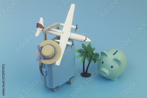 Travel suitcase with beach hat, umbrella, coconut palm and airplane model on blue background.  Airplane tickets price, vacation and travel concept.