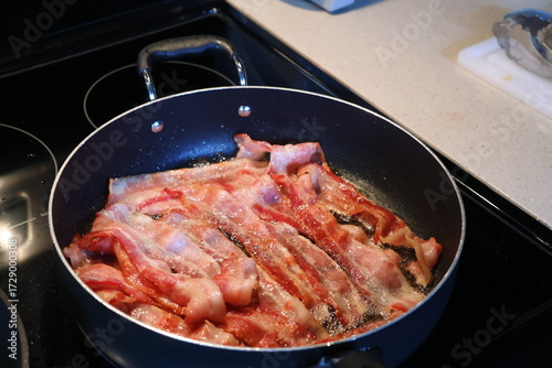 Foto multiple slices juicy bacon sizzling on the frying pan.