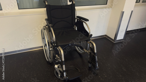 Modern black wheelchair with metal frame and comfortable seat, medical mobility aid for hospital, rehabilitation, clinic, healthcare, disability support equipment, accessible transport indoors close u