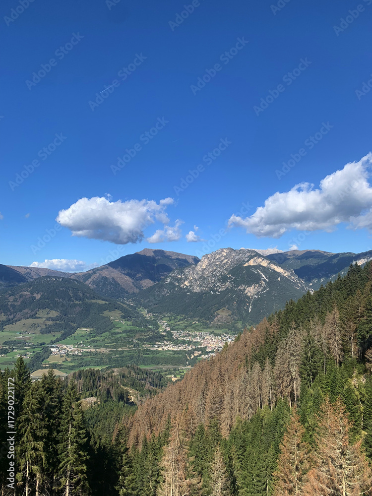 Obraz premium Mountain town surrounded by green valley and rocky peaks