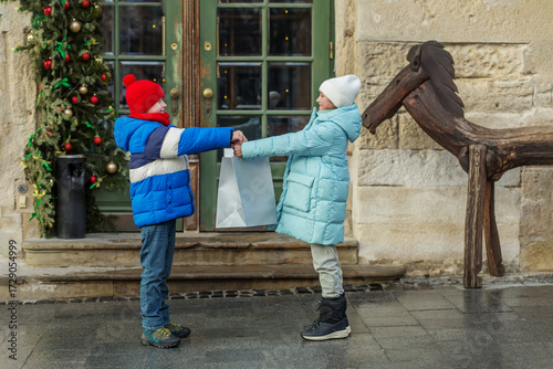 Kids exchanging gift bag outside during winter holidays