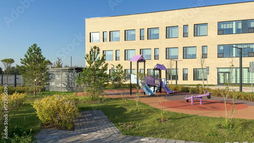 Foto Modern kindergarten school territory with outdoor playground, colorful slides, swings, landscaped greenery, rubber