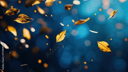 Golden leaves falling against a blue background with bokeh effect.