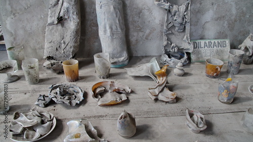 Discarded plastic cups and wrappers litter a dusty surface, creating a scene of environmental neglect and waste disposal in an urban setting.