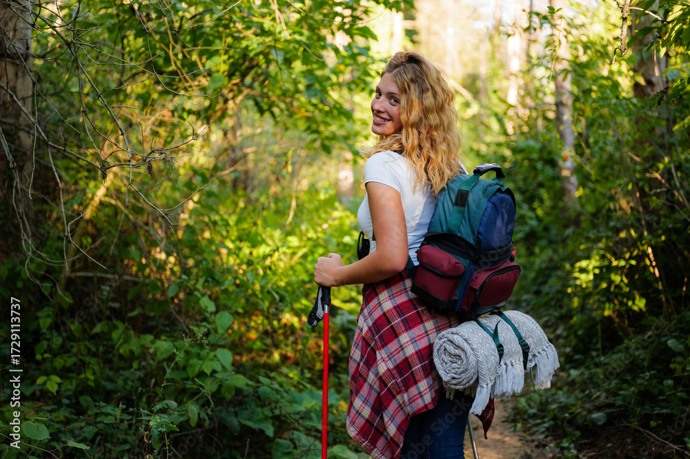 Obraz premium Young woman hiking actively in green forest turning smiling