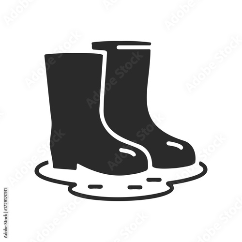 Black icon of rain boots standing in puddle on white background