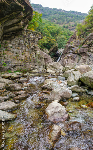 Mountain stream with rocks and small waterfall in alpine gorge, Valle d’Aosta, Italy