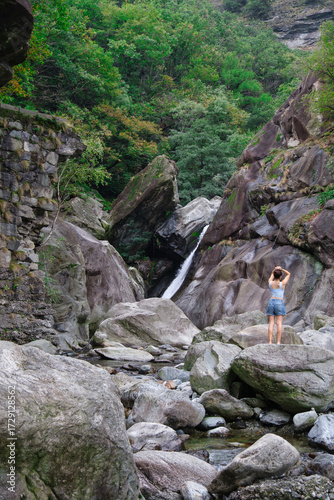 Woman admiring waterfall in alpine gorge, Valle d’Aosta, Italy.