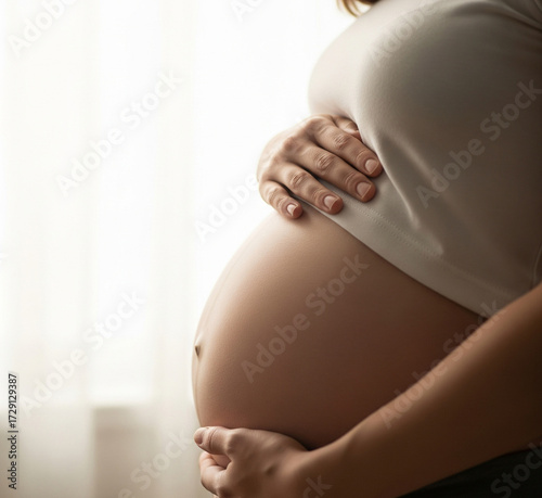 Low angle shot of pregnant woman caressing her baby bump, outdoor natural light, emotional maternity moment
