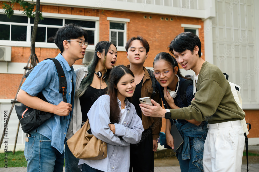 Obraz premium A group of diverse university students gather around a smartphone, smiling and sharing excitement, symbolizing digital connection, inclusion, and friendship in modern campus life