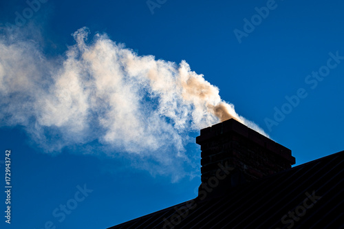 Smoke from the chimney of a single-family house
