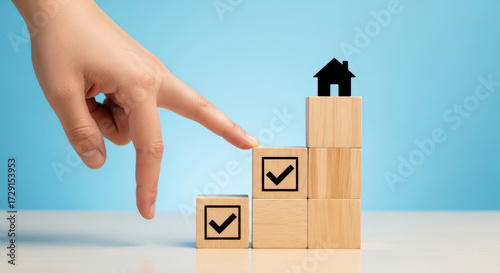 Achieving Goals Step by Step A Hand Reaching for a House on Top of Wooden Blocks Symbolizing Progress and Success in Real Estate and Personal Development