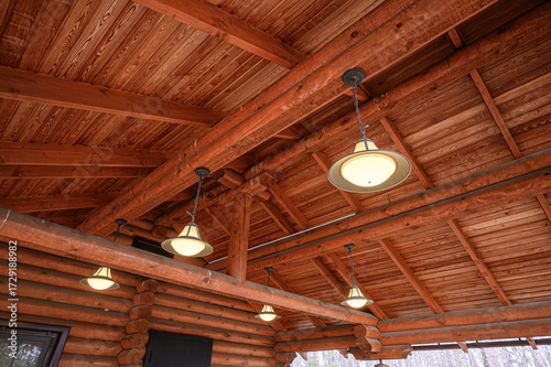Exposed wooden beams and ceiling with warm pendant lights in a rustic log cabin interior