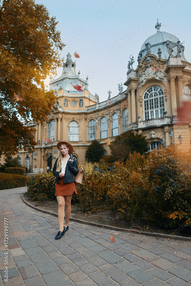 Obraz premium Young woman in leather jacket and skirt enjoying travel near medieval castle.